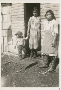 Image of Eskimo [Inuk] woman and children in front of their house